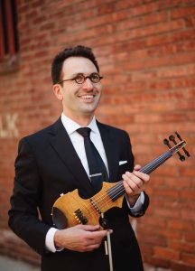 Happy man holding instrument in front of brick wall