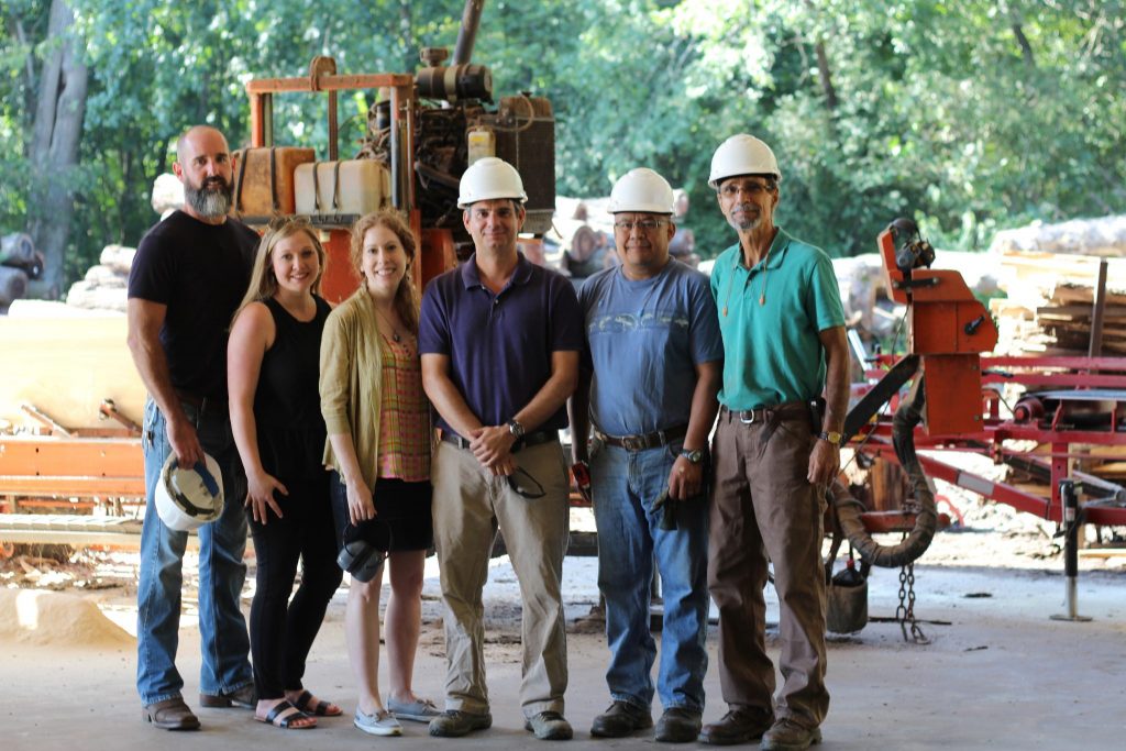 Happy people smiling outside in front of machinery