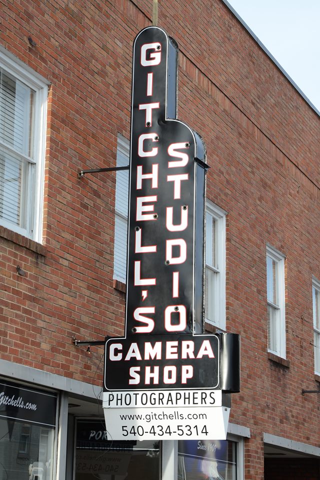 Camera shop neon sign on brick building