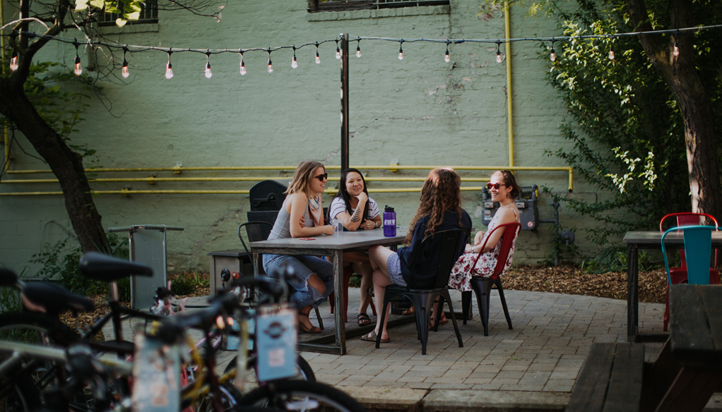 Women smiling and chatting on outdoor patio
