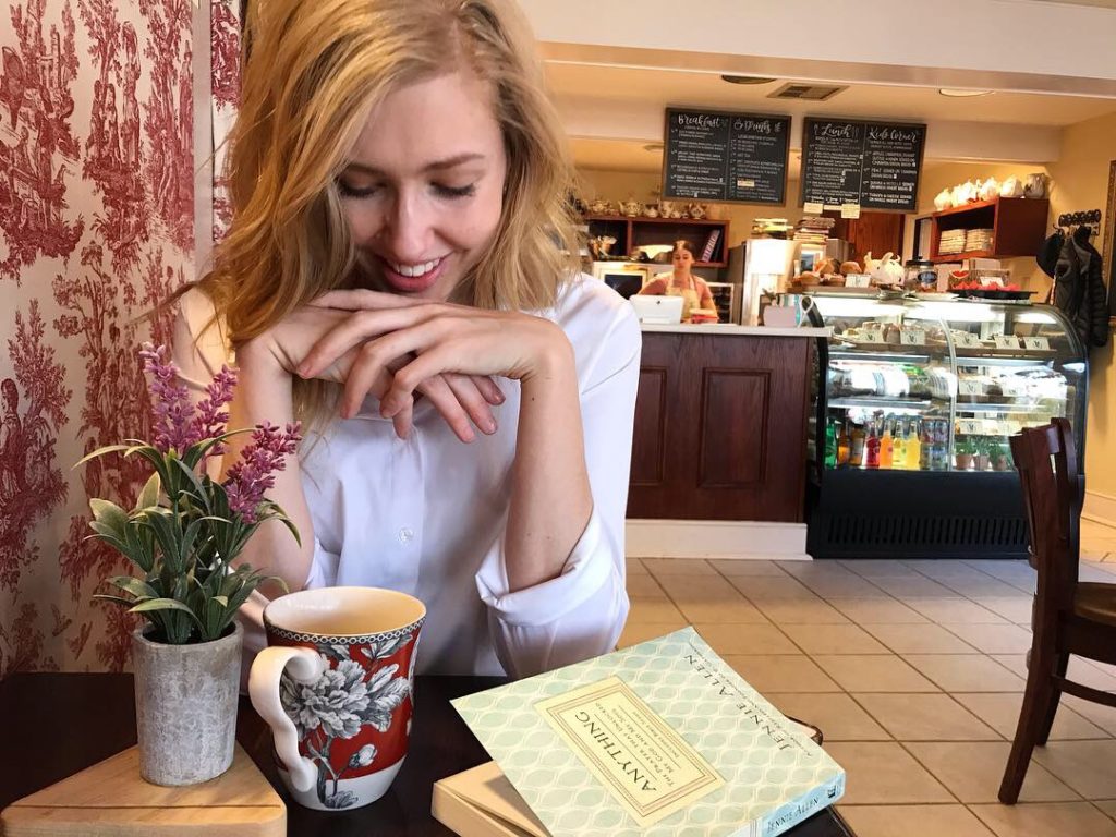 Smiling woman at local bakery with tea and book