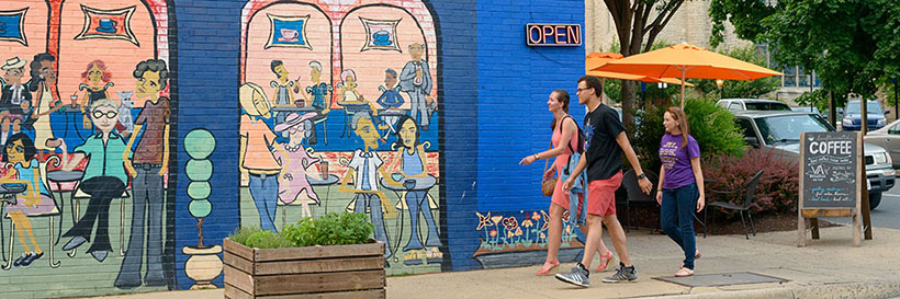 Happy people walking in front of colorful mural downtown