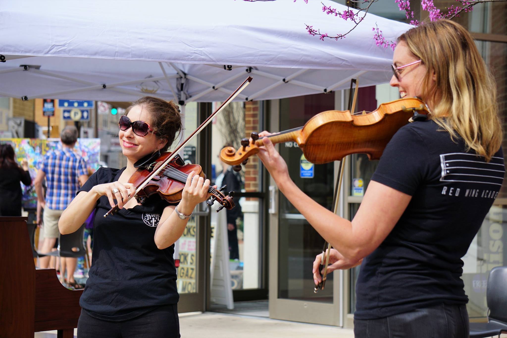 Women smiling playing violins at music event