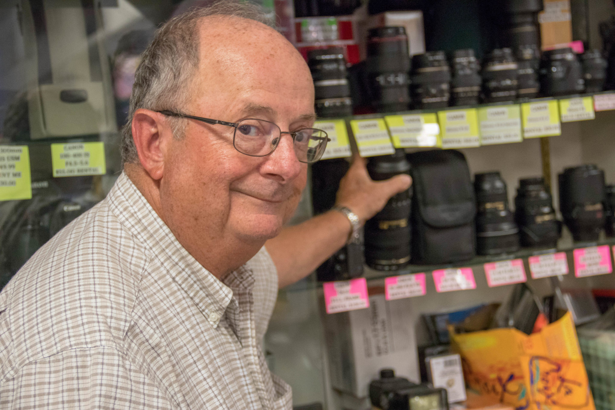 Owner of Glens Fair Price Store reaching for camera lenses