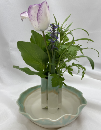Blue and white vase with purple flowers and green leaves