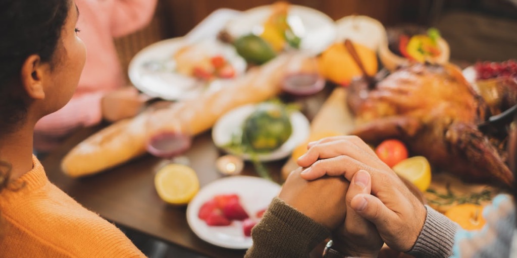 people holding hands around a table of food