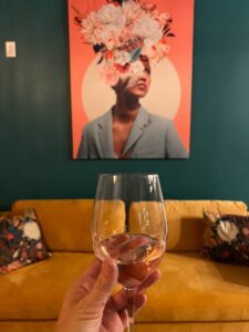 An image of someone holding their wine glass up for a picture in front of wall art featured at Rootstock.